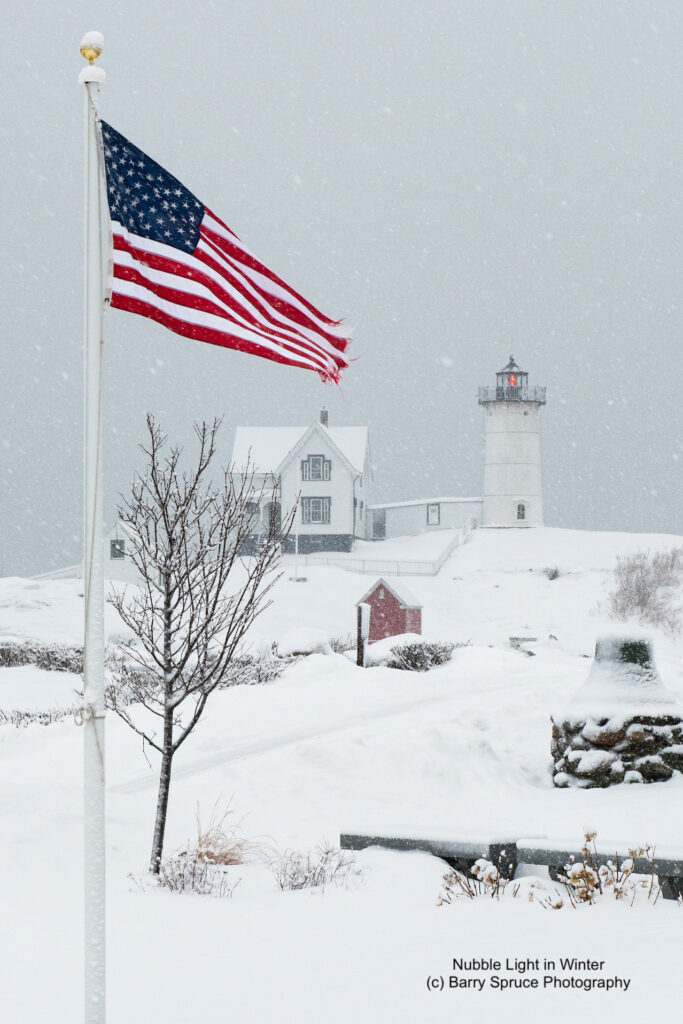 Lighthouse in snow storm with colorful American Flag.